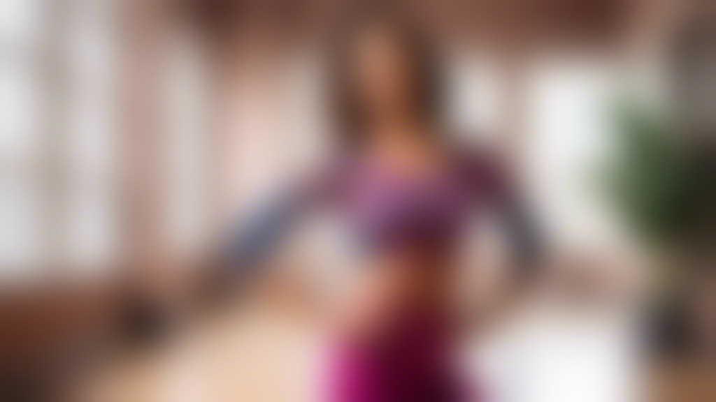 A stylish woman wearing a premium dance top designed for salsa dancing, showcasing the top's flattering fit, vibrant colors, and elegant details. The environment is a dance studio with a sleek and mod