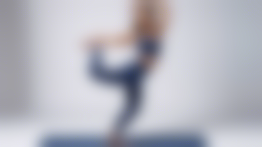 A graceful dancer moves through effortless leaps and glides, clad in the perfect yoga pants for both comfort and style. The pants are a rich deep blue, with subtle details that catch the light as she 